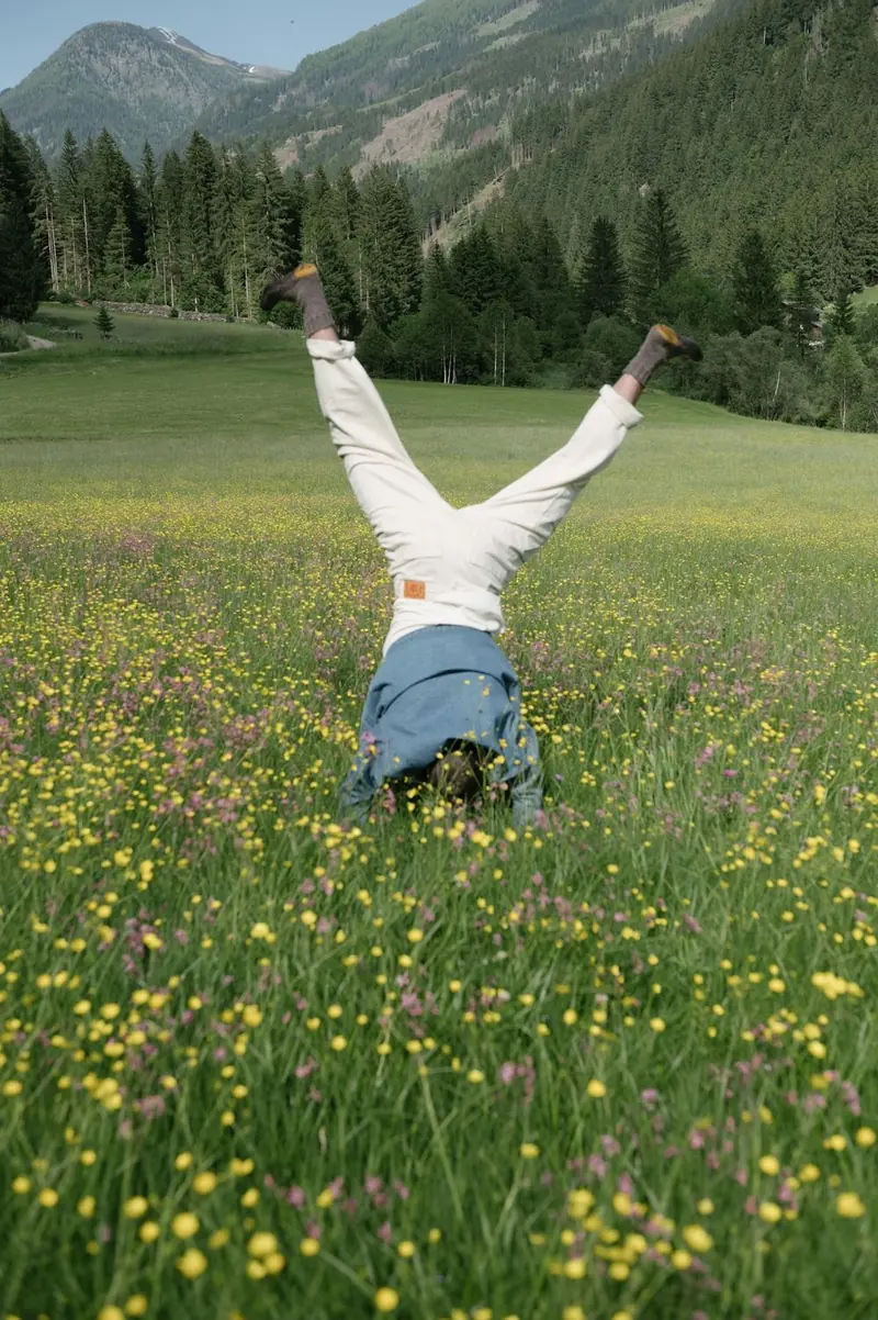 Someone doing a headstand in a meadow of wildflowers